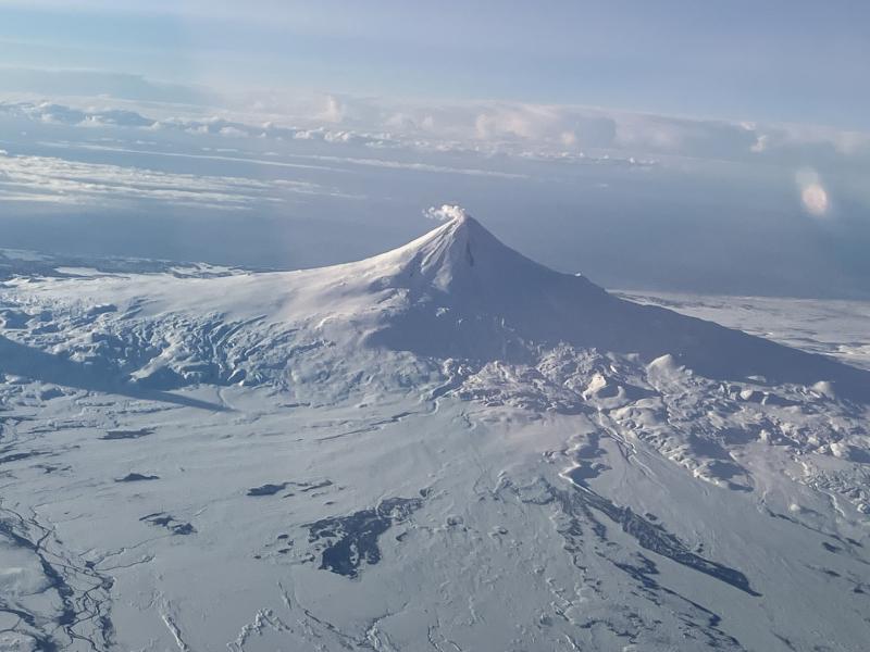 Images of the north side of Shishaldin Volcano on February 20, 2024 from a passing flight showing light steaming from the summit and a snow-free area over cooling deposits on a northeast drainage. 