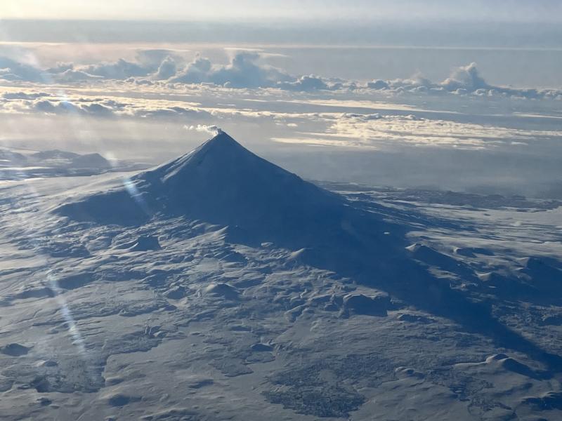 Images of the north side of Shishaldin Volcano on February 20, 2024 from a passing flight showing light steaming from the summit and a snow-free area over cooling deposits on a northeast drainage. 