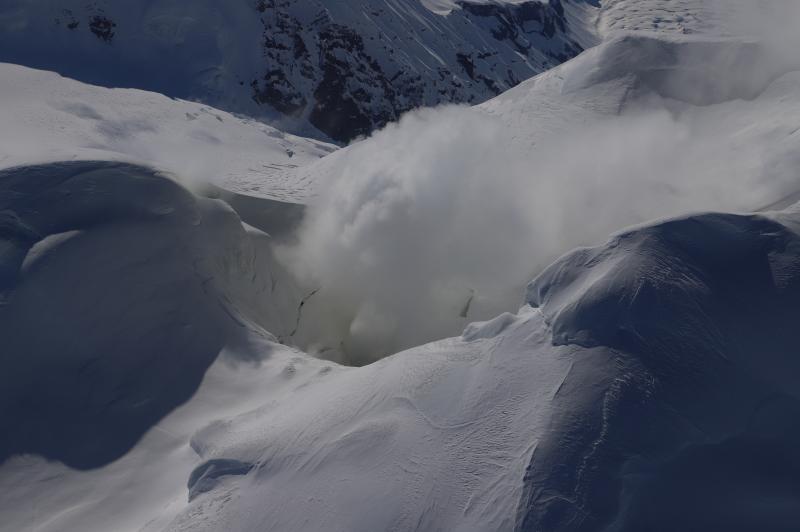 Steaming from the summit crater at Mount Spurr is visible during an overflight on May 14, 2024. The primary steam source is a fumarole (steam vent) inside of the summit crater, but a smaller fumarole is visible on the northeast crater rim. The snow is yellow around both fumaroles, where sulfur is precipitating on the snow from the plume.