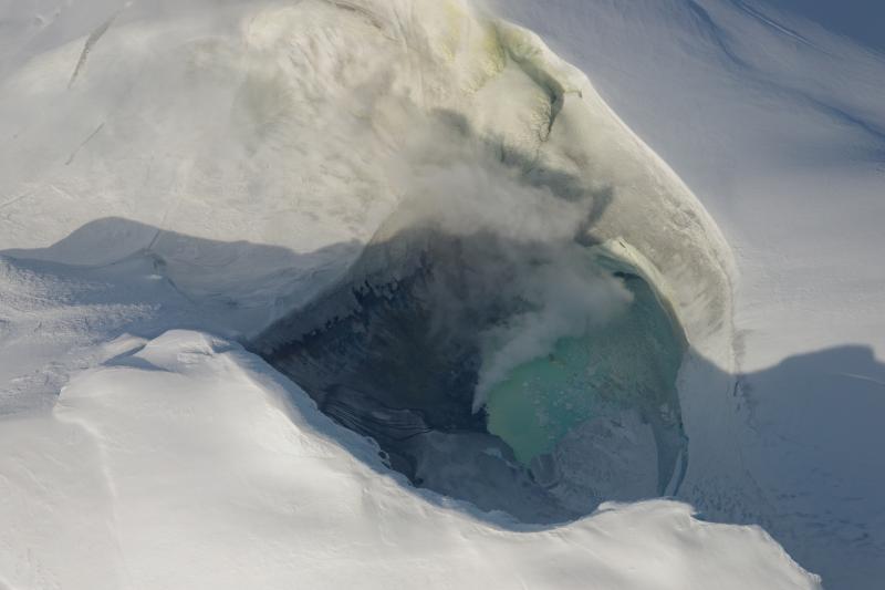 Crater lake visible at the summit of Mount Spurr, along with degassing fumaroles on the lake shore.