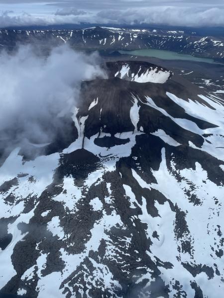 Vent Mountain with a cloud drifting above the crater. Surprise Lake can be seen in the distance, as well as Vent Mountain lava and scoria in the foreground. View toward the NE.