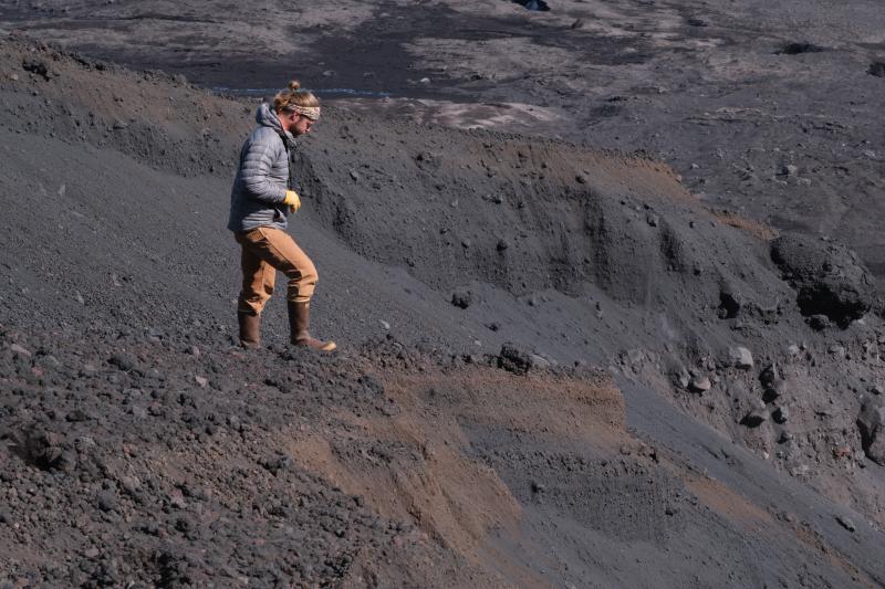 AVO geologist Jordan Lubbers standing on proximal pyroclastic flow deposits on the northeast flank of Shishaldin during geologic observation and sampling work on July 30, 2024.