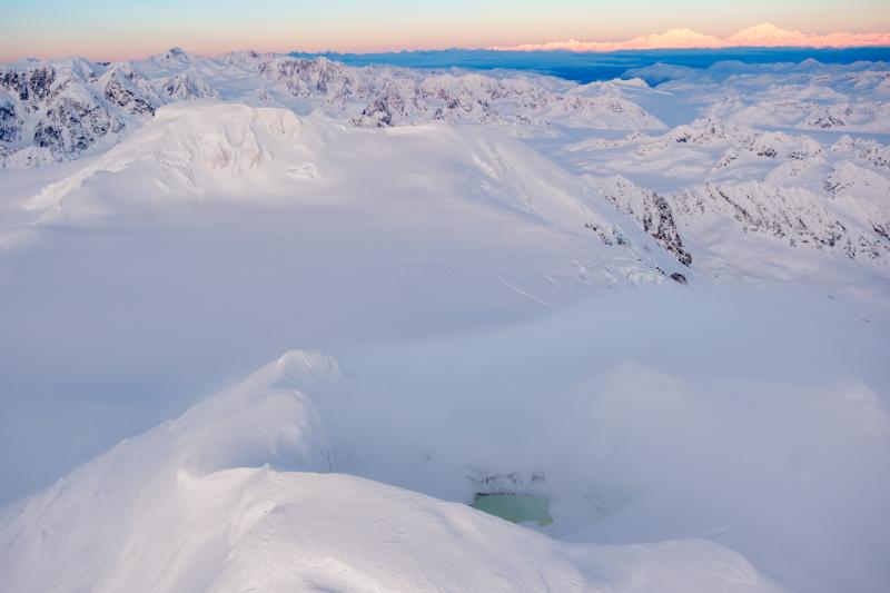 Mount Spurr summit and its crater lake (bottom) with Denali on the horizon in the upper right. 