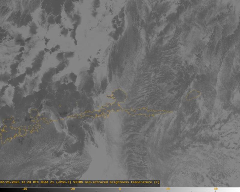 This is a mid-infrared satellite image of Atka Island and surroundings captured at 13:23 UTC Feb 21 2025 (4:23 AM AKST). Coast outlines are in yellow. The various shades of gray correspond to the temperature of objects in the scene, with the scale at the bottom in degrees Celsius. Clouds and land are darker gray (cooler) than the ocean surface. The summit lake at Korovin Volcano is visible as a tiny spot of lighter gray on the northern side of Atka Island. Lakes, like the ocean, typically differ a bit in temperature from the land surface and are thus visible in mid-infrared images.