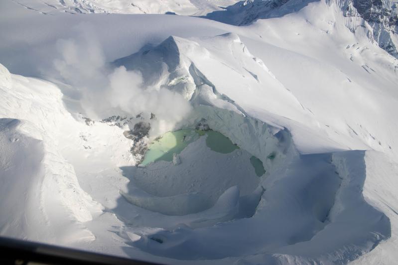 Lake inside of the Mount Spurr summit crater with fumaroles and discolored water on March 21, 2025. Much of the lake surface is covered in snow and ice, but three ice-free regions are present around fumaroles. 