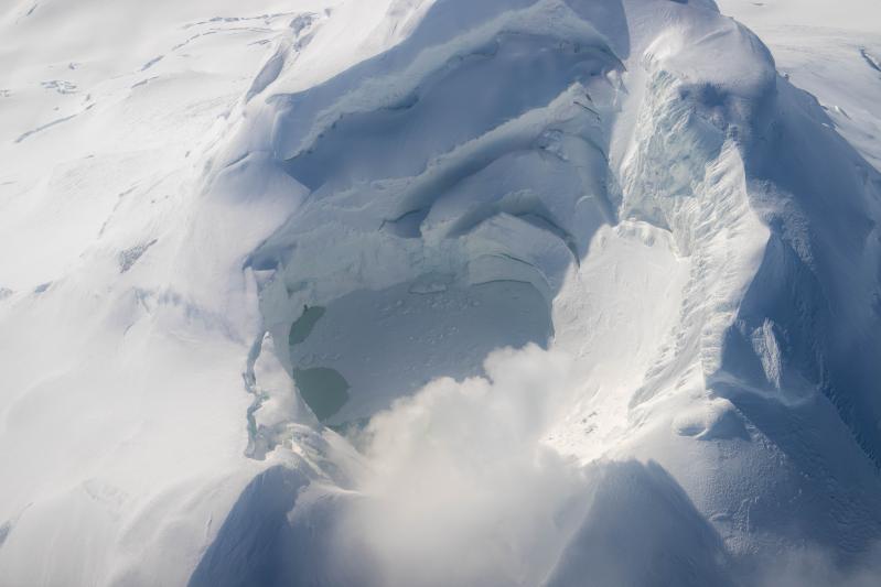 Lake inside of the Mount Spurr summit crater with fumaroles and discolored water on March 21, 2025. Much of the lake surface is covered in snow and ice.