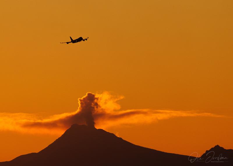 Photo of steam emissions from the summit of Mount Spurr with a departing 747 aircraft in the foreground. Mount Spurr is located about 80 miles west of Anchorage, Alaska and is the 4th busiest air cargo airport in the world.