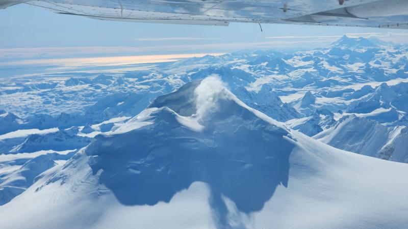 View of Mount Spurr summit, taken March 21, 2025, from the north. Steam is rising from the fumaroles on the shore of the lake inside the summit crater and on the upper flanks. Redoubt Volcano and Iliamna Volcano (behind Redoubt) are visible on the horizon (right).