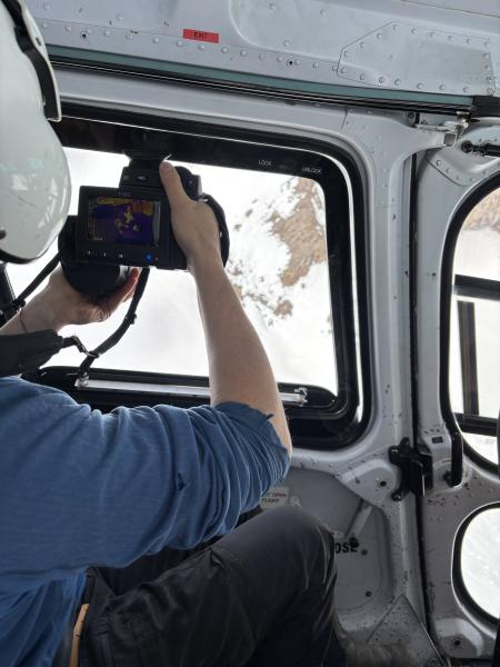 An Alaska Volcano Observatory scientist uses a thermal camera to measure ground and steam vent temperatures during an overflight of Crater Peak at Mount Spurr on May 23, 2025.