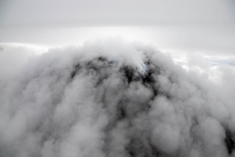 The active lava dome (black mound) at Great Sitkin is seen steaming (bright white steam) amidst ground-hugging clouds during an Alaska Volcano Observatory overflight on September 2, 2025
