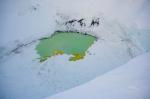 Summit crater of Mount Spurr with a partially ice-covered crater lake on December 18, 2024. Yellow sulfur precipitates are visible floating on the surface. Photo taken during a photo and gas survey following recent seismic unrest at the volcano.