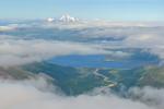 View east along the Alaska-Aleutian volcanic arc from near Roundtop Mountain. False Pass is visible in the gap below the clouds. Peaks along the horizon from right to left: Dutton, Frosty, Pavlof, Pavlof Sister. 