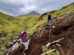 AVO geologists M. Coombs and H. Dietterich photographing the tephra section at station 25AAHD003. Mount Sarichef is in the background. 